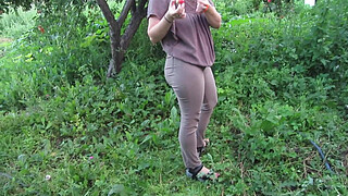 MILF pee in tight pants in a public park open air. Dirty cunt squatting pissing in the yard.