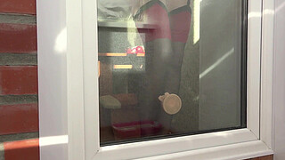 A neighbor watches through the window, as a MILF fucks herself with a dildo by the balcony door. Beautiful ass in doggy style.