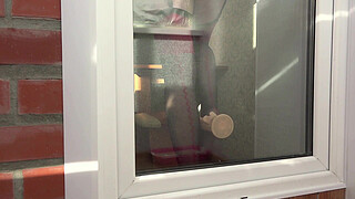 A neighbor watches through the window, as a MILF fucks herself with a dildo by the balcony door. Beautiful ass in doggy style.